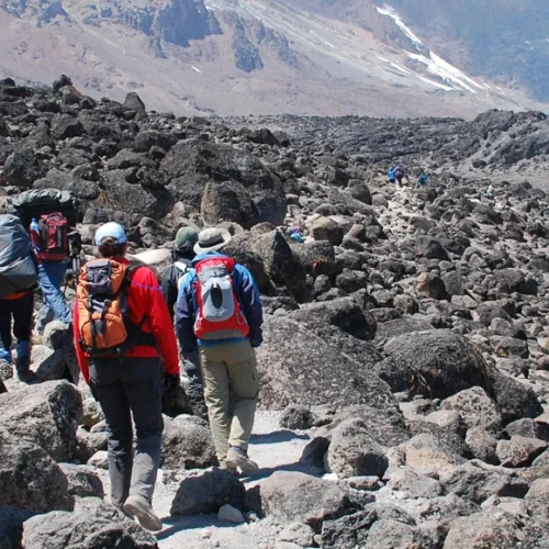 Kilimanjaro machame route climbers crossing rocky volcanic mountain trail