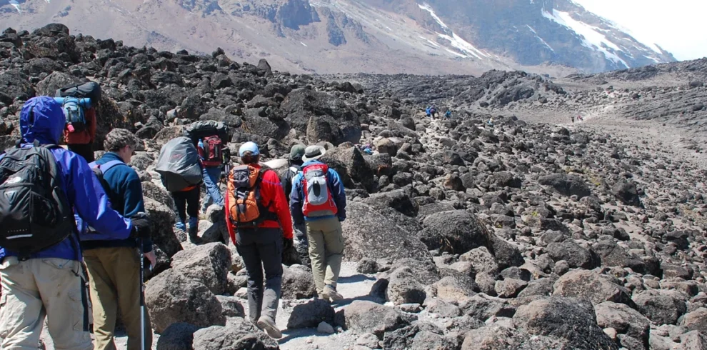 Kilimanjaro machame route climbers crossing rocky volcanic mountain trail