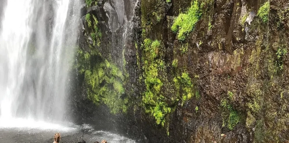 Materuni waterfall visitors beneath scenic cascade near kilimanjaro tanzania