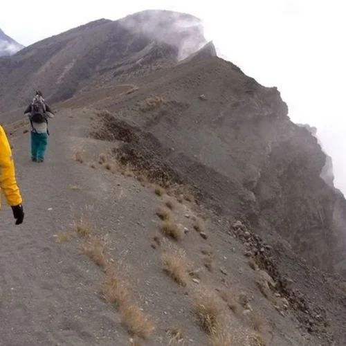Mount meru climber walking rugged crater ridge above clouds tanzania