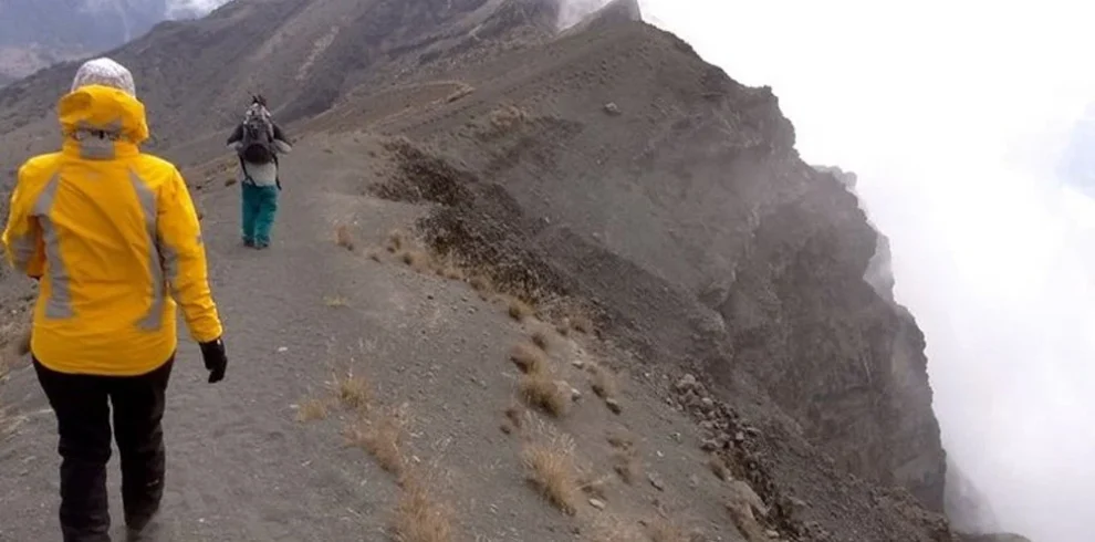 Mount meru climber walking rugged crater ridge above clouds tanzania