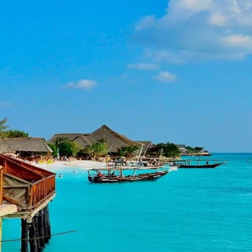 Zanzibar oceanfront lodge with traditional dhow boats on turquoise Indian Ocean water