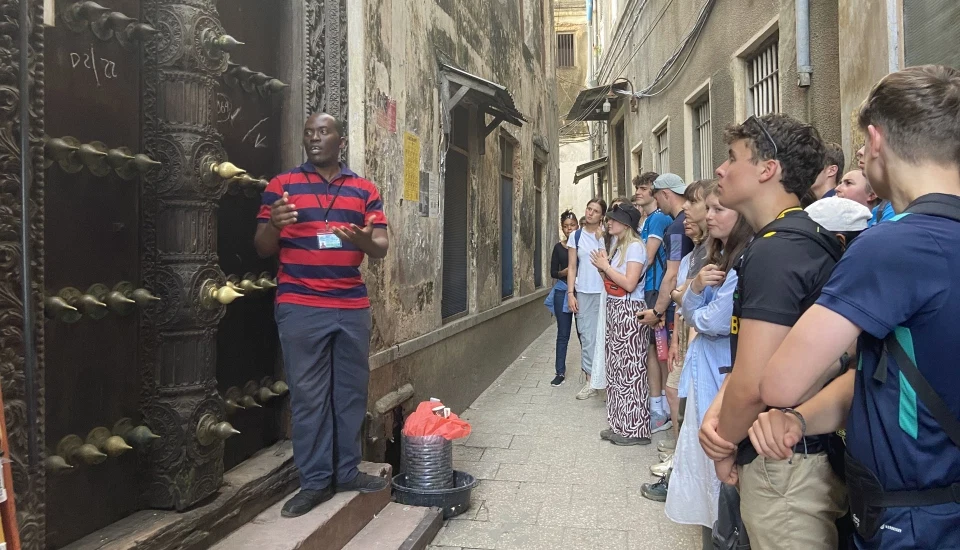 Visitors walking through a historic narrow street in Stone Town Zanzibar